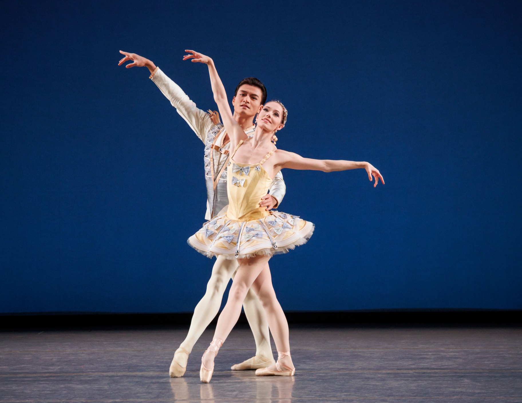 Divertimento No. 15 series — Divertimento No. 15 — partnered pose with ballerina in yellow tutu and cavalier in pale blue against deep blue backdrop